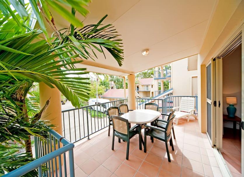 At Beach Court Holiday Villas in Airlie Beach, covered balcony with table, chairs and tropical greenery