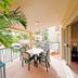 At Beach Court Holiday Villas in Airlie Beach, covered balcony with table, chairs and tropical greenery