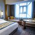 Henan Sky-Land Gdh Hotel in Zhengzhou guest room with king bed, window seat, and city view