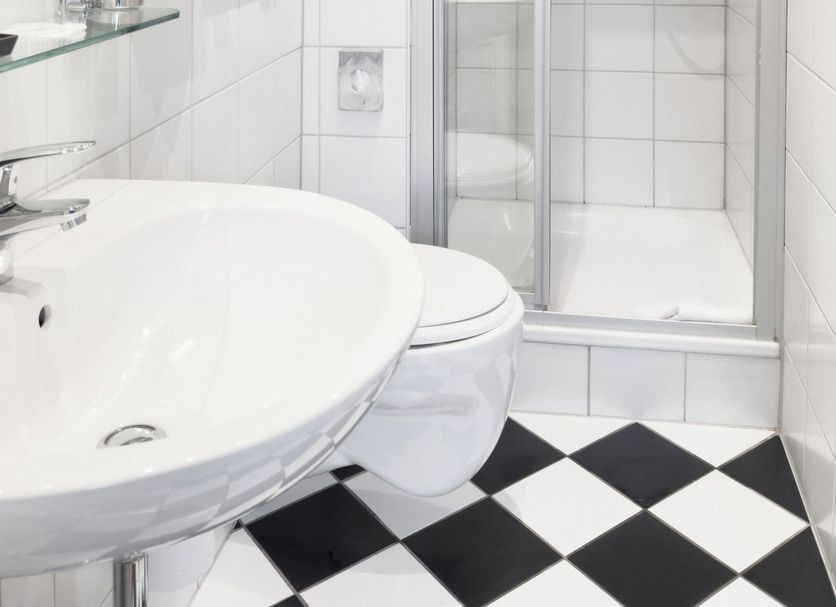 Hotel Weisses Haus Bad Kissingen bathroom with glass shower, pedestal sink and black-and-white tile floor