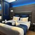 Hôtel Clairefontaine Paris guest room with blue accents, king bed, and arched mirror