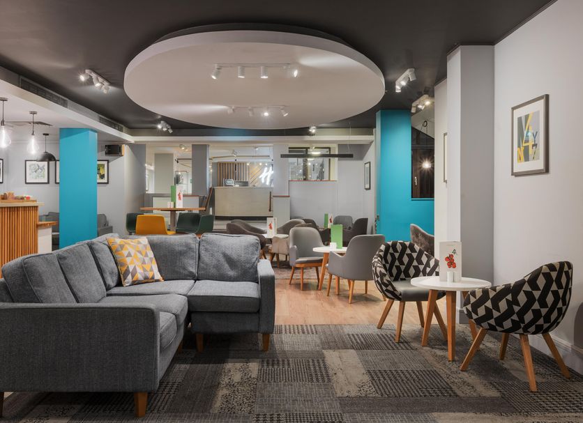 Holiday Inn Northampton By IHG lounge with sectional seating, colorful chairs and modern lighting