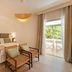 Ostuni a Mare in Ostuni: bright room with bed, wicker chairs and a balcony view of greenery