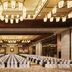 Hilton Qingdao Golden Beach ballroom in Qingdao with rows of white-covered chairs and chandeliers