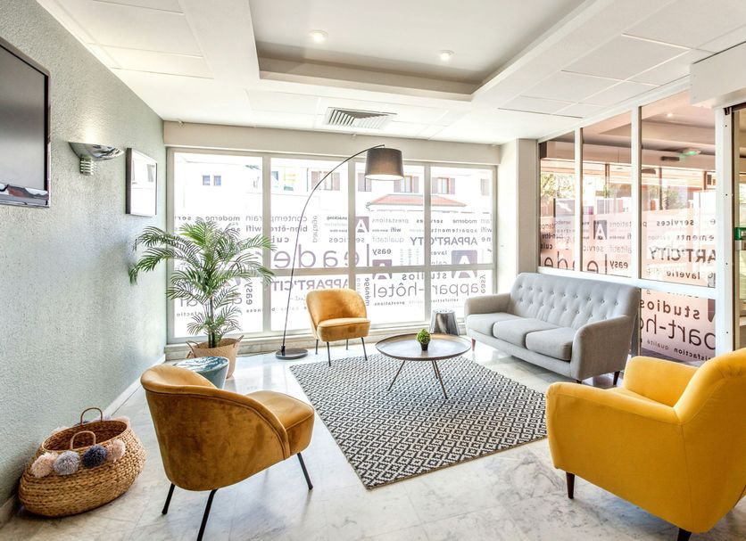 Lobby seating area at Appart'City Classic Genève - Gaillard with gray sofa, yellow chairs and plant