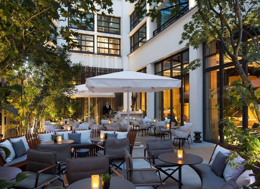 Le Cinq Codet Paris courtyard terrace with lounge seating, tables, umbrellas and warm evening lighting