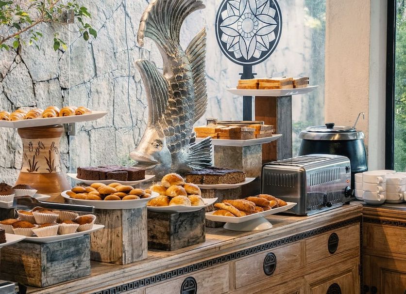 Skyloft Kandy buffet table with pastries and bread beside a decorative bird sculpture in Kandy