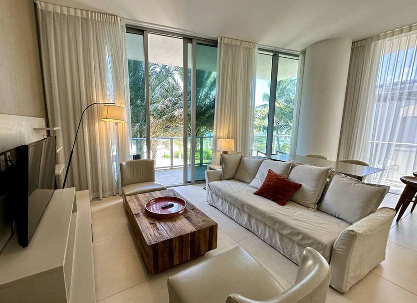 Lyfe Resort And Residences in Hollywood living room with sofa, TV, floor lamp and sliding doors to palm-view patio