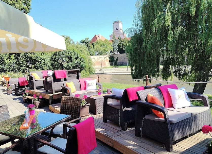 Hotel Icon Győr patio with wicker seating, pink cushions and a view of greenery and a tower