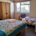 Avoncourt Lodge in Ilfracombe bedroom with two single beds, a window, and chairs by the wall