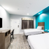 Scottish Inns & Suites - Kingwood guest room in Humble with two beds and bright turquoise accent wall