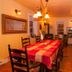 Gîte Au Coin De La Berge dining room in Percé with long table, wood stove, staircase and warm lighting
