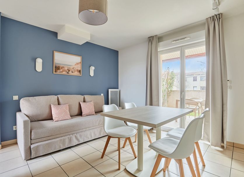 Résidence Odalys Le Mas des Flamants in Aigues-Mortes: bright apartment living area with balcony doors