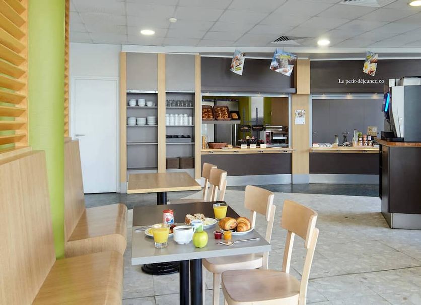 B&B HOTEL Paris Roissy CDG Aéroport breakfast area with tables, chairs, and buffet counter in Roissy-en-France