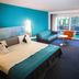 Le Bristol Leukerbad room with teal accent wall, bed, sofa, desk and large window view