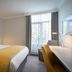 Maldron Hotel Dublin Airport guest room with king bed, desk, armchair, and window with curtains in Dublin