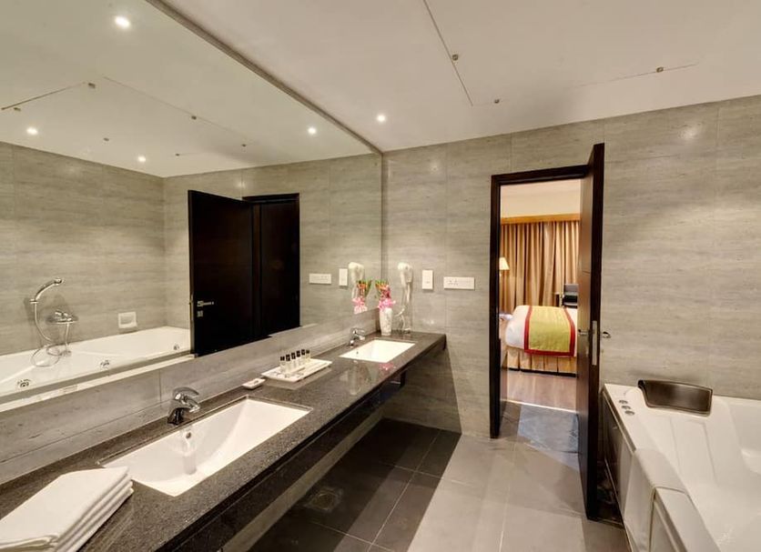 Hotel Combermere in Shimla bathroom with double vanity, mirror and bathtub, open to bedroom