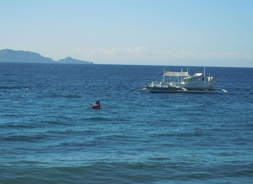 Wellbeach Dive Resort in Dauin with ocean view, small boat on blue sea and distant islands