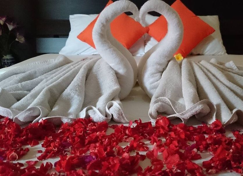 Agus Beach Inn, Kuta: swan towel art on a bed with red rose petals and orange pillows