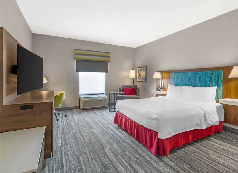 Hampton Inn Junction City guest room with king bed, wall-mounted TV, window, desk and lamps