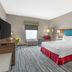 Hampton Inn Junction City guest room with king bed, wall-mounted TV, window, desk and lamps