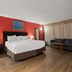Quality Inn Wayne - Fairfield Area guest room with king bed, sofa, lamps, and wood-look flooring in Wayne
