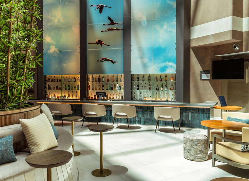 Delta Hotels by Marriott Olbia Sardinia lounge with bar, tall windows and potted bamboo in Olbia