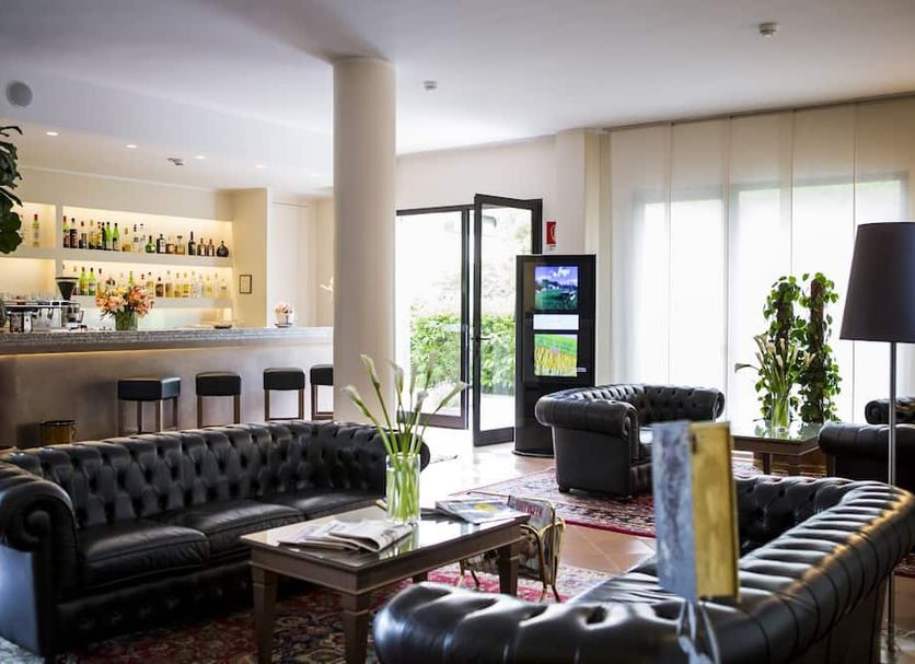 Hotel City Piacenza lounge with black leather sofas, bar, and glass doors to outdoor seating