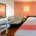 Motel 6 Mammoth Lakes guest room with bed, booth seating, table and orange accent wall