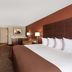 Baymont by Wyndham Midland Airport guest room with king bed, TV, dresser and sitting chair in Midland