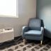 Lakewood Inn & Suites in Dowagiac guest room with blue armchair, lamp, and patterned carpet