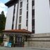 Flora Daisy Apartment in Borovets with white facade, red-tiled entrance canopy and balconies