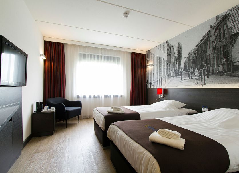 Bastion Hotel Zoetermeer guest room with two twin beds, window seat and black-and-white city mural