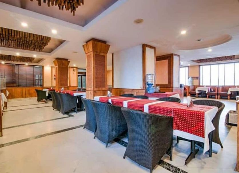 Hotel Devi Grand in Katra dining room with set tables, wicker chairs, and bright windows