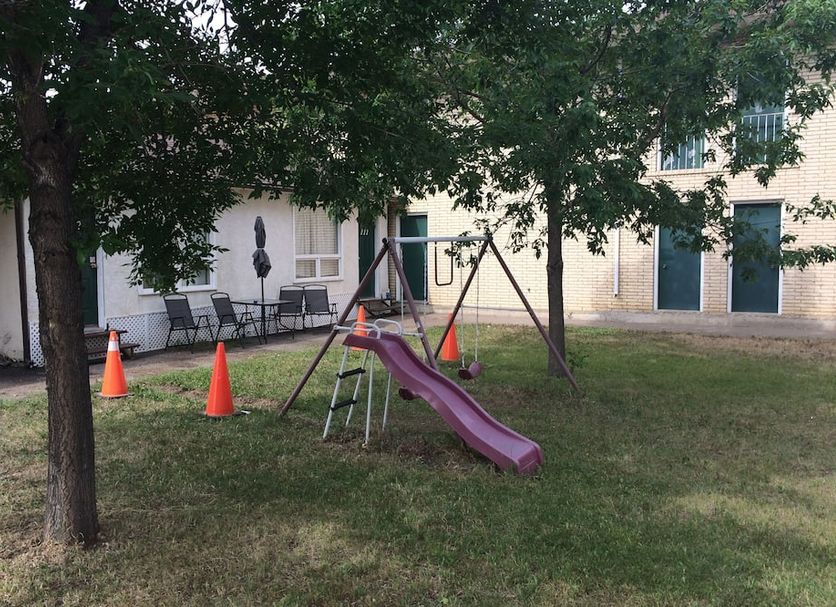 Pals Motel and RV Park in Medicine Hat with a small playground and swings outside the building