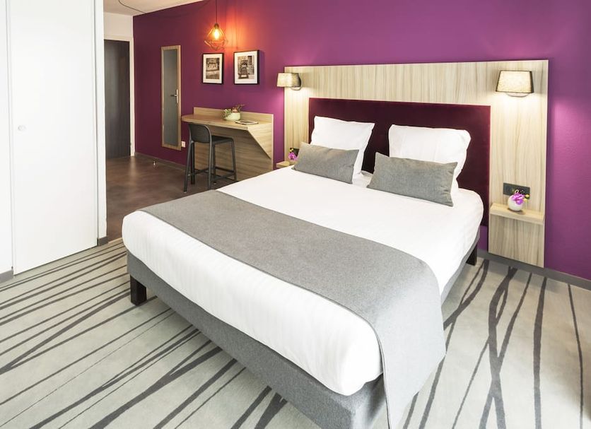 Nemea Appart Hotel Stadium Bordeaux aéroport in Mérignac: modern room with bed, desk and purple accent wall