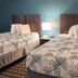 Motel 6 Crowley, La room with two beds, patterned bedding, and a bedside lamp in Crowley
