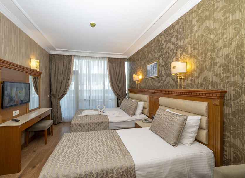 Dalan Hotel Istanbul guest room with two twin beds, desk, patterned wallpaper and window curtains