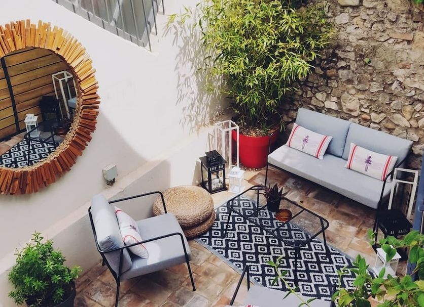 La Maison Grivolas in Avignon, a cozy courtyard terrace with seating, patterned rug and stone wall