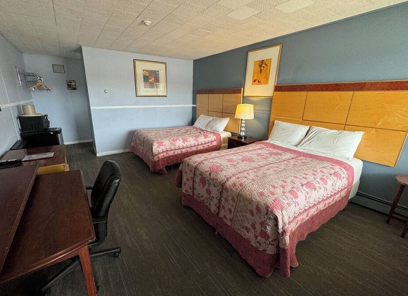 Travel Inn Cochrane guest room with two beds, desk, and lamp in Cochrane