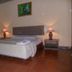 Bali Lovina Beach Cottages in Buleleng guest room with bed, bedside lamps, and terracotta tile floor