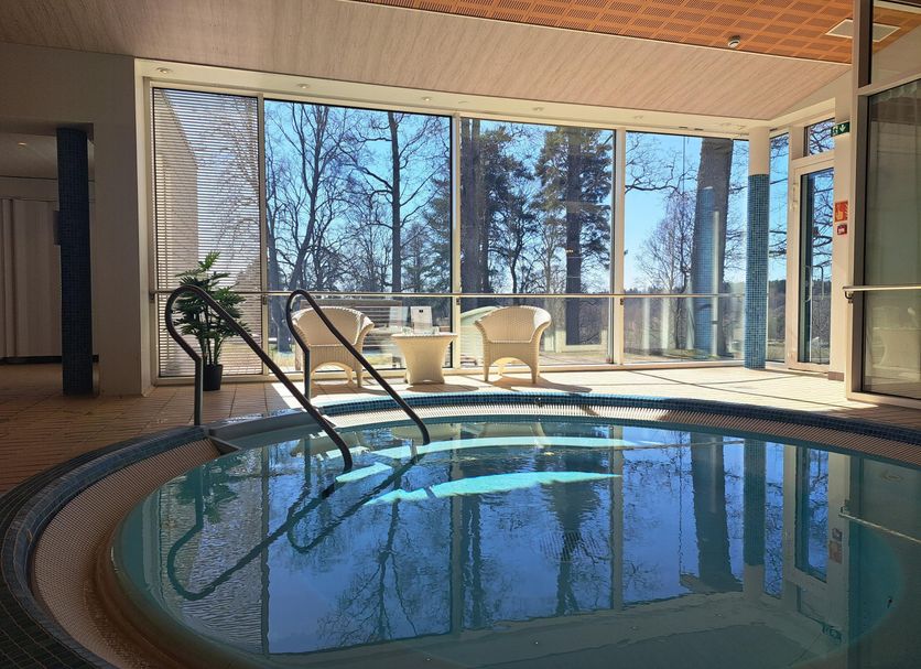 Backby Manor in Espoo: indoor pool with large windows and lounge chairs overlooking trees