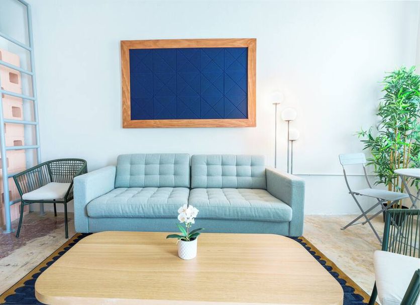 Romeo Hotel in San Juan lounge with blue sofa, coffee table, ladder shelf, and potted plant