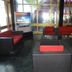 Hotel Airport Centre Point, Nagpur: lounge seating with red and black chairs and a TV in a glass-walled area