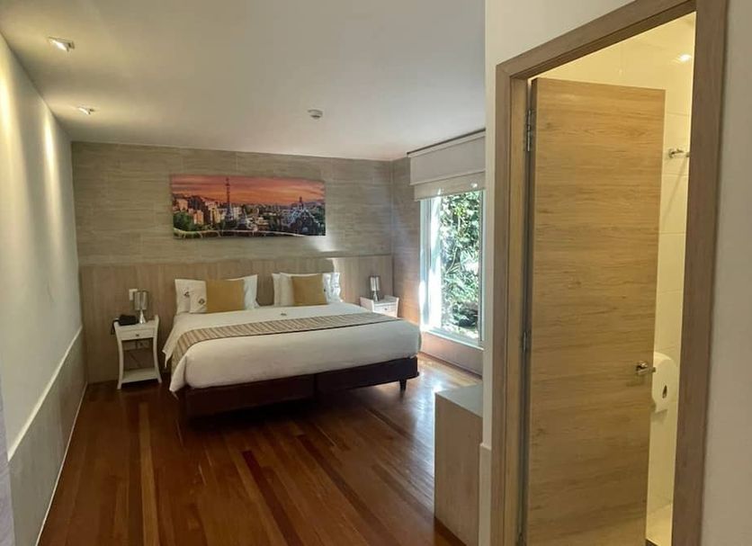 Casa Hotel Boyaca Real, Bogotá guest room with king bed, wood floors and large window