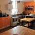 Abel's Central Backpackers kitchen in Nelson with orange cabinets, stove, sink and prep tables