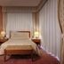 Borgo Palace Hotel in Sansepolcro guest room with queen bed, bedside lamps, and floor-to-ceiling curtains