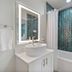 Bridgewalk, a Landmark Resort bathroom with teal tile shower, tub, and illuminated mirror in Bradenton Beach