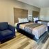 Harrisonville Inn & Suites Harrisonville guest room with two beds, blue chair and wood-look flooring