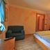 Hotel Tita Piaz in Canazei: cozy guest room with double bed, armchair, bedside tables and warm lighting